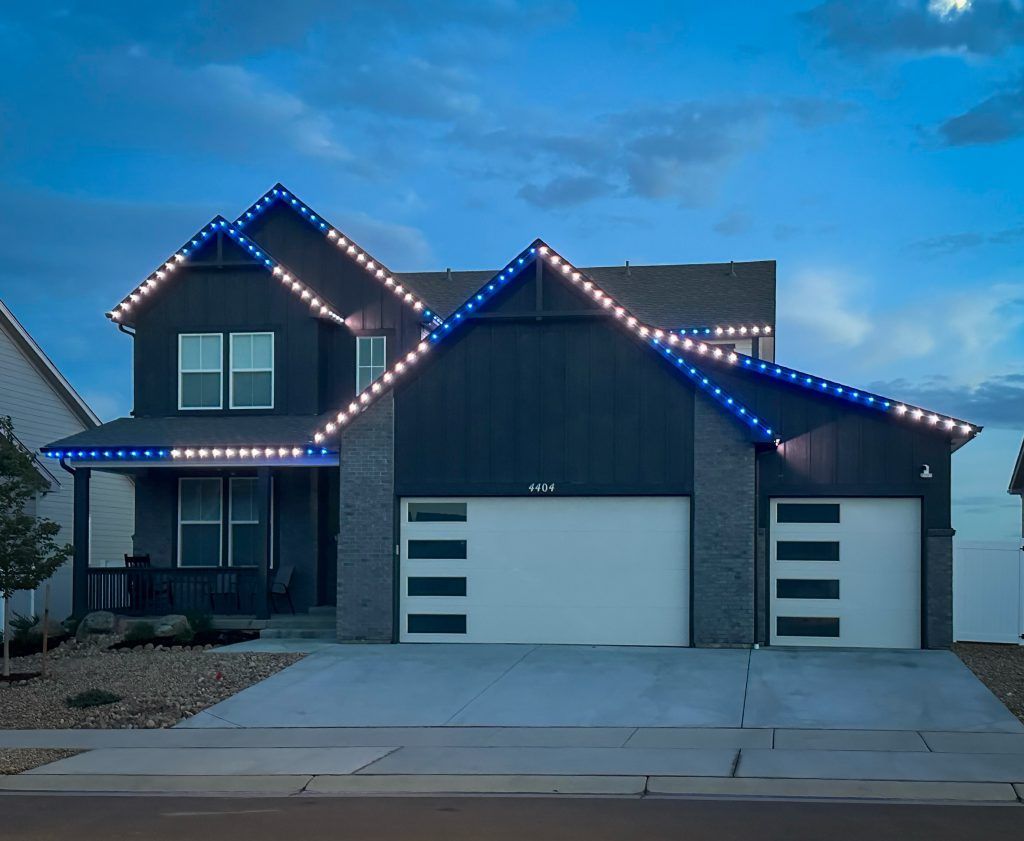 Two-story house at dusk with blue roofline lights and a white garage