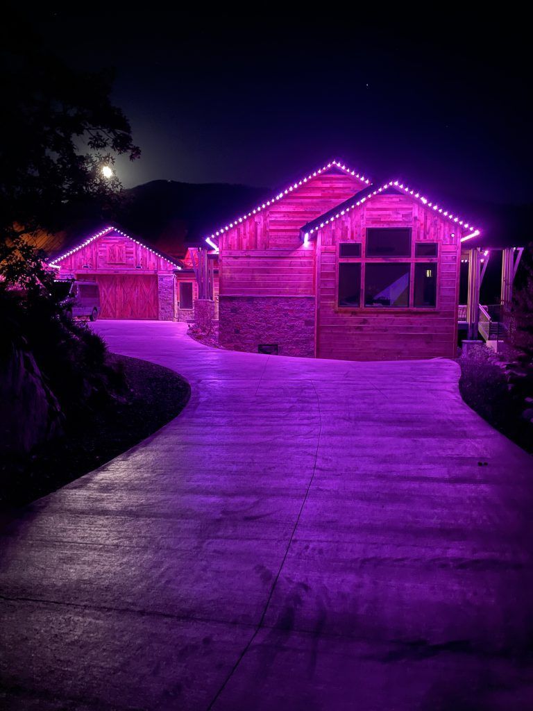 Brick house and driveway lit with purple lights at night