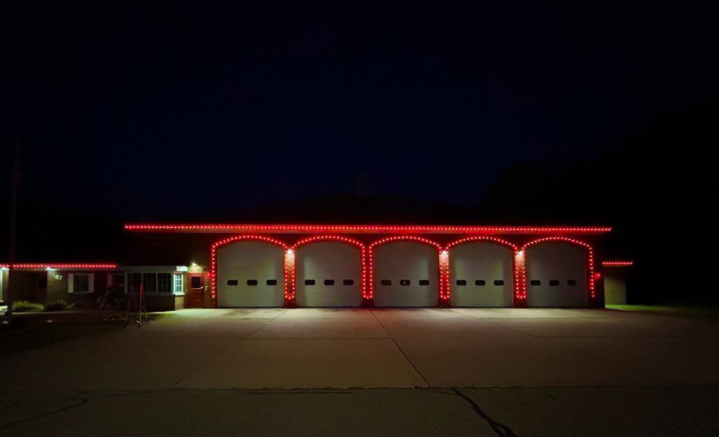 Red-lit fire station with four garage bays at night
