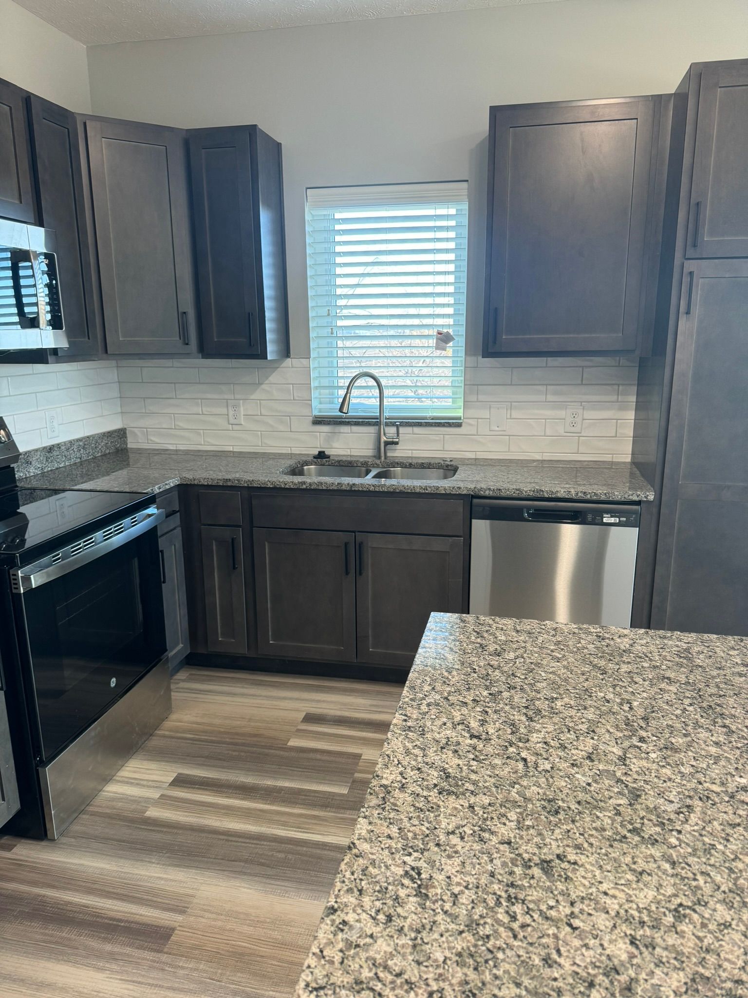Kitchen with dark cabinets, stainless steel appliances, and granite countertops.