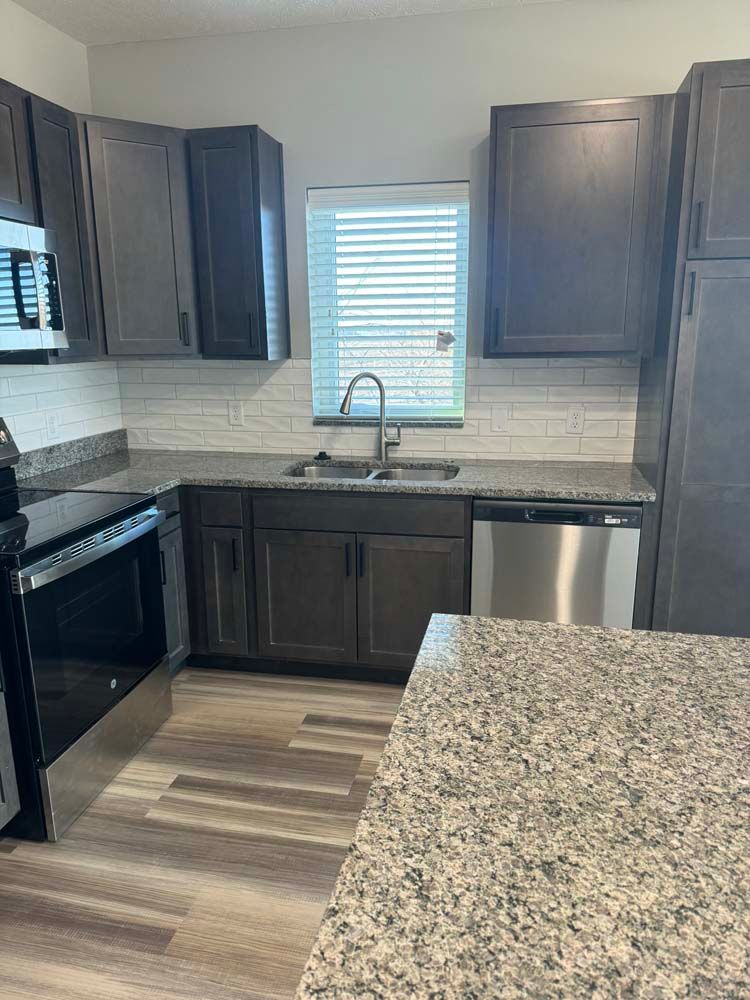 Kitchen with dark cabinets, stainless steel appliances, and granite countertops.