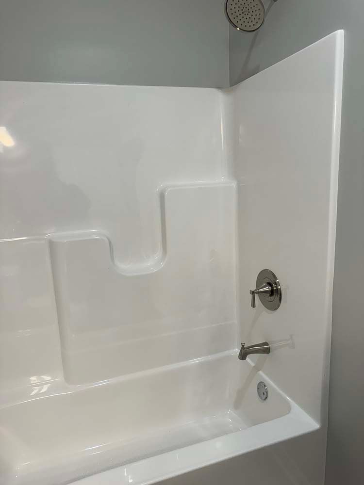 White bathtub and shower surround with silver fixtures.