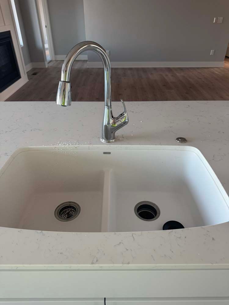 White double kitchen sink with chrome faucet on white countertop.