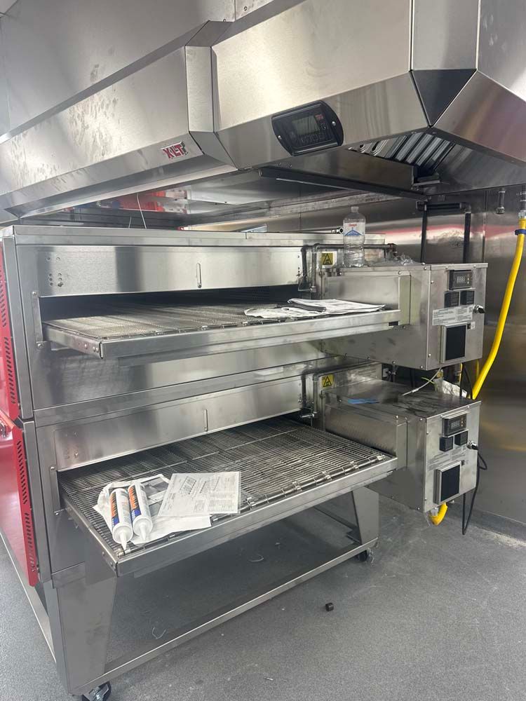 Commercial oven with two shelves, stainless steel, under a hood. Red side panel.
