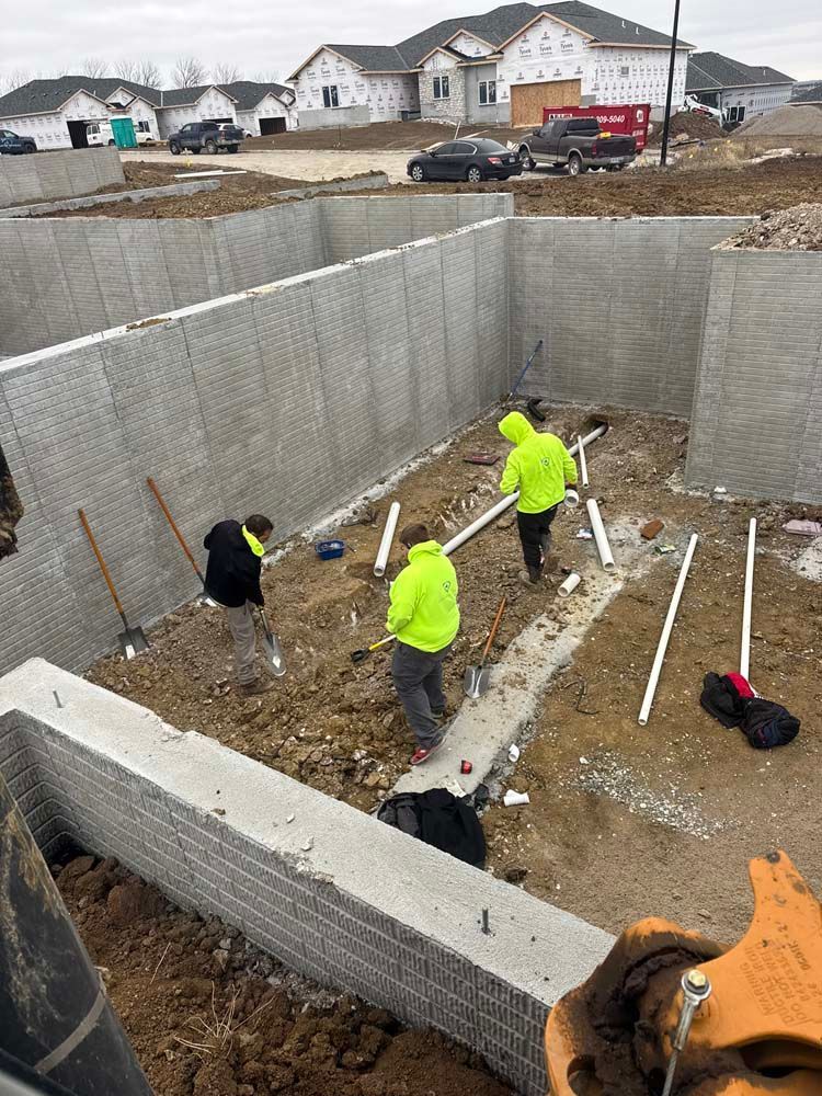 Construction workers installing plumbing in a basement foundation at a new construction site.