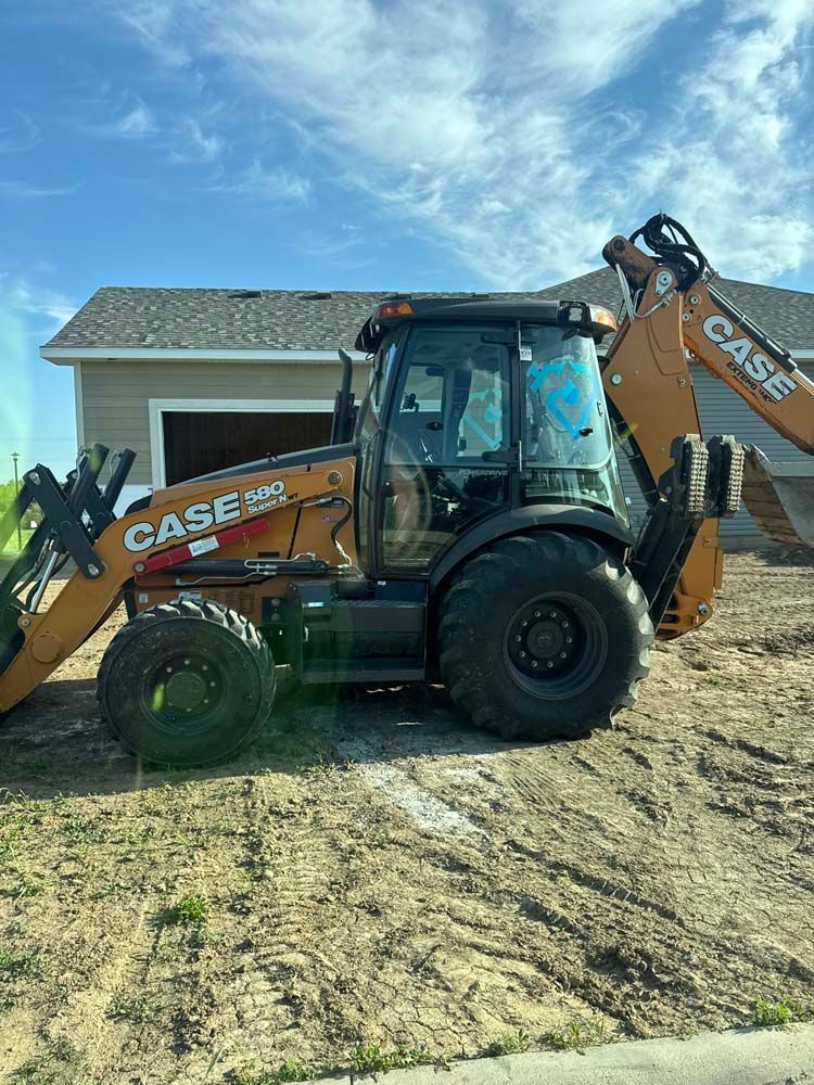 Case 580 backhoe on a construction site with a building in the background, against a blue sky.