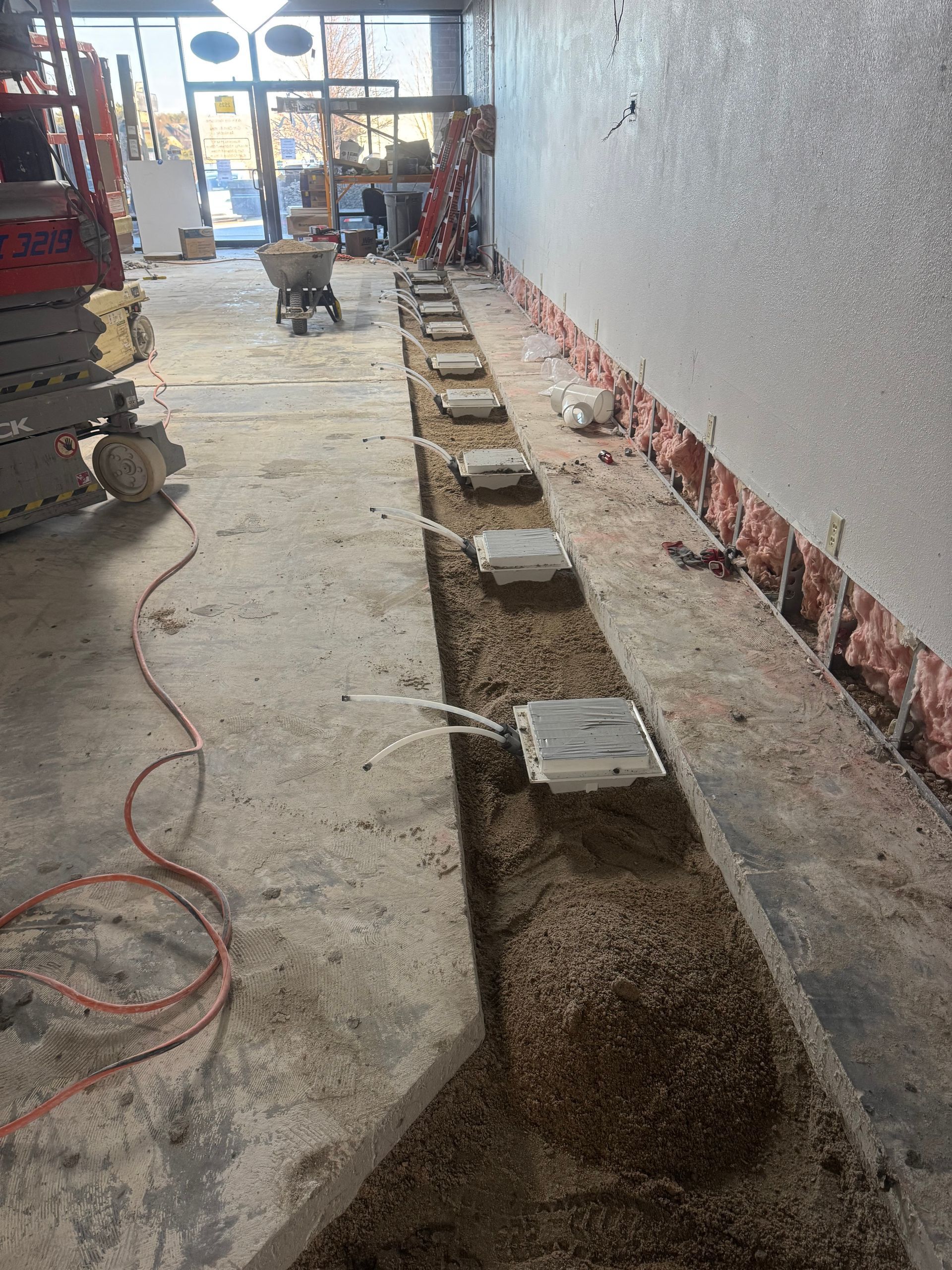 Construction site: concrete floor with a trench holding electrical outlets. A shop interior is under renovation.