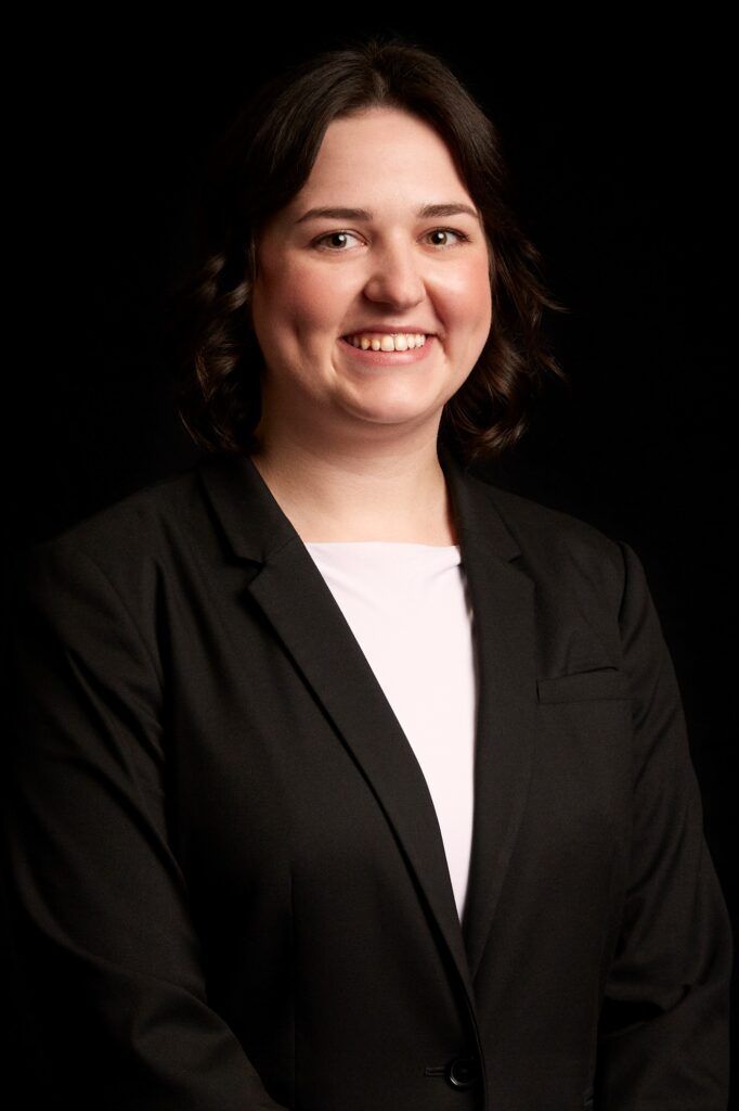 A woman in a black suit and white shirt is smiling for the camera.