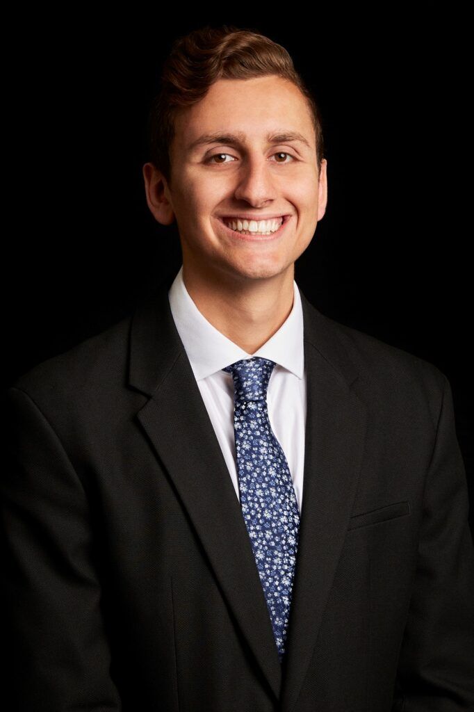 A young man in a suit and tie is smiling for the camera.