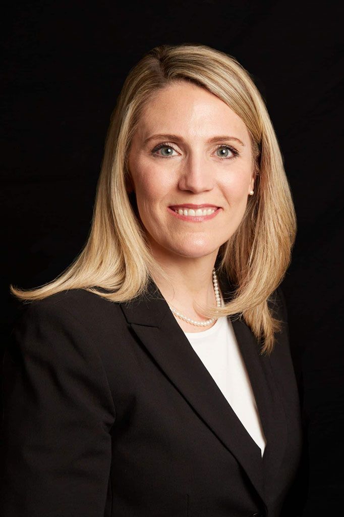 A woman in a black suit and white shirt is smiling for the camera.