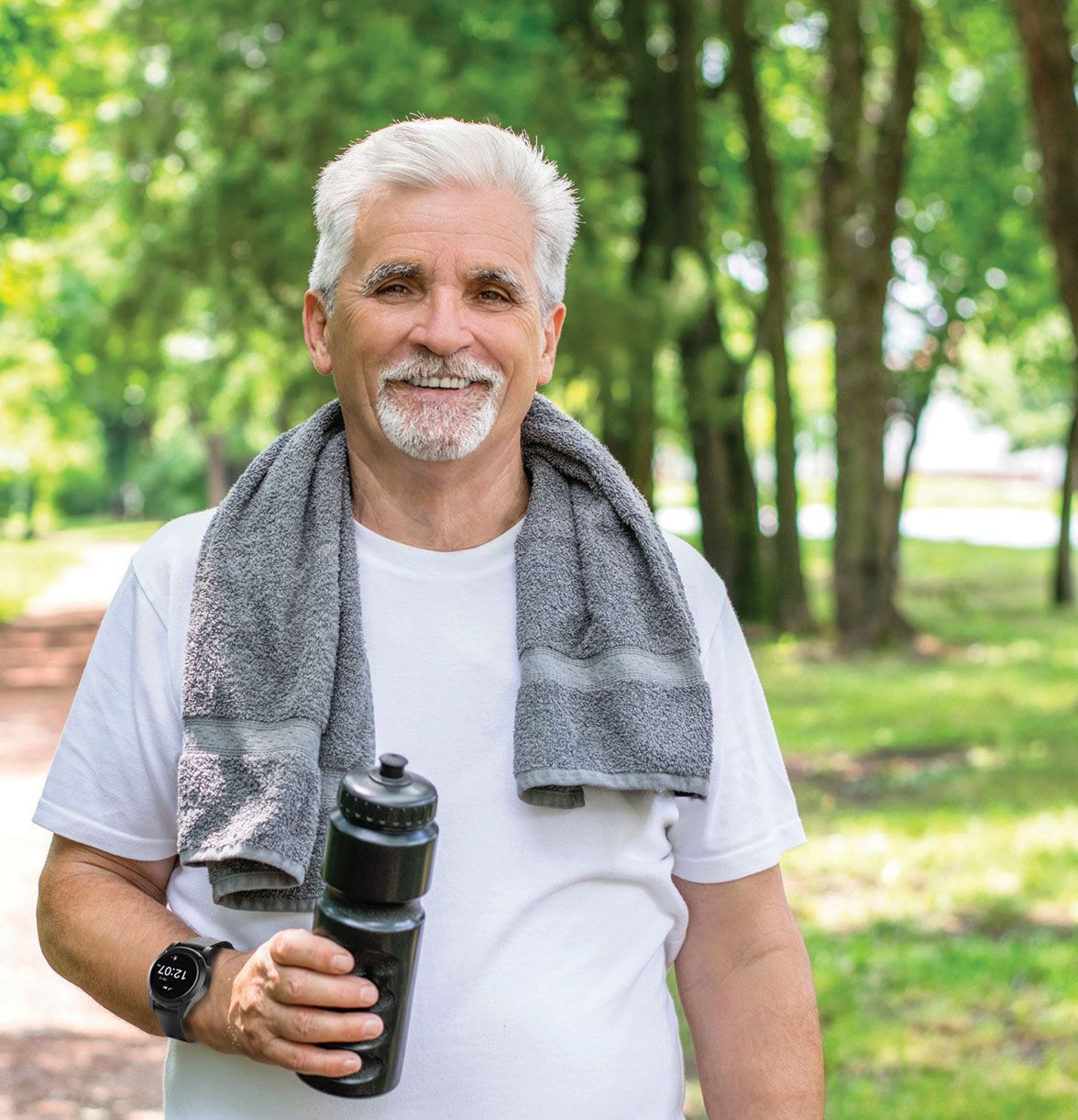 A man with a towel around his neck is wearing sidekick smartwatch