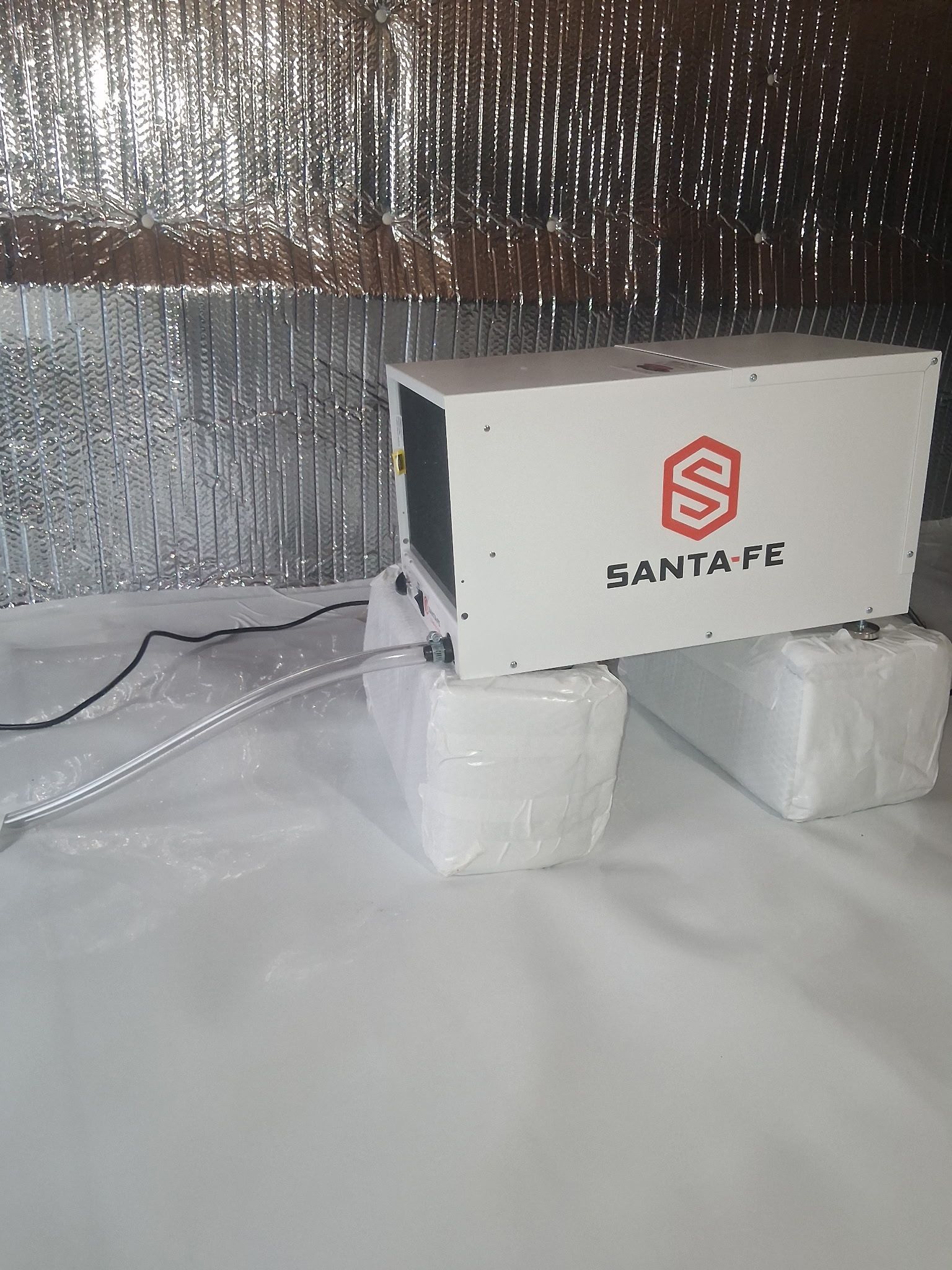 White Santa Fé box on two foam blocks against a reflective silver backdrop with cables on the floor