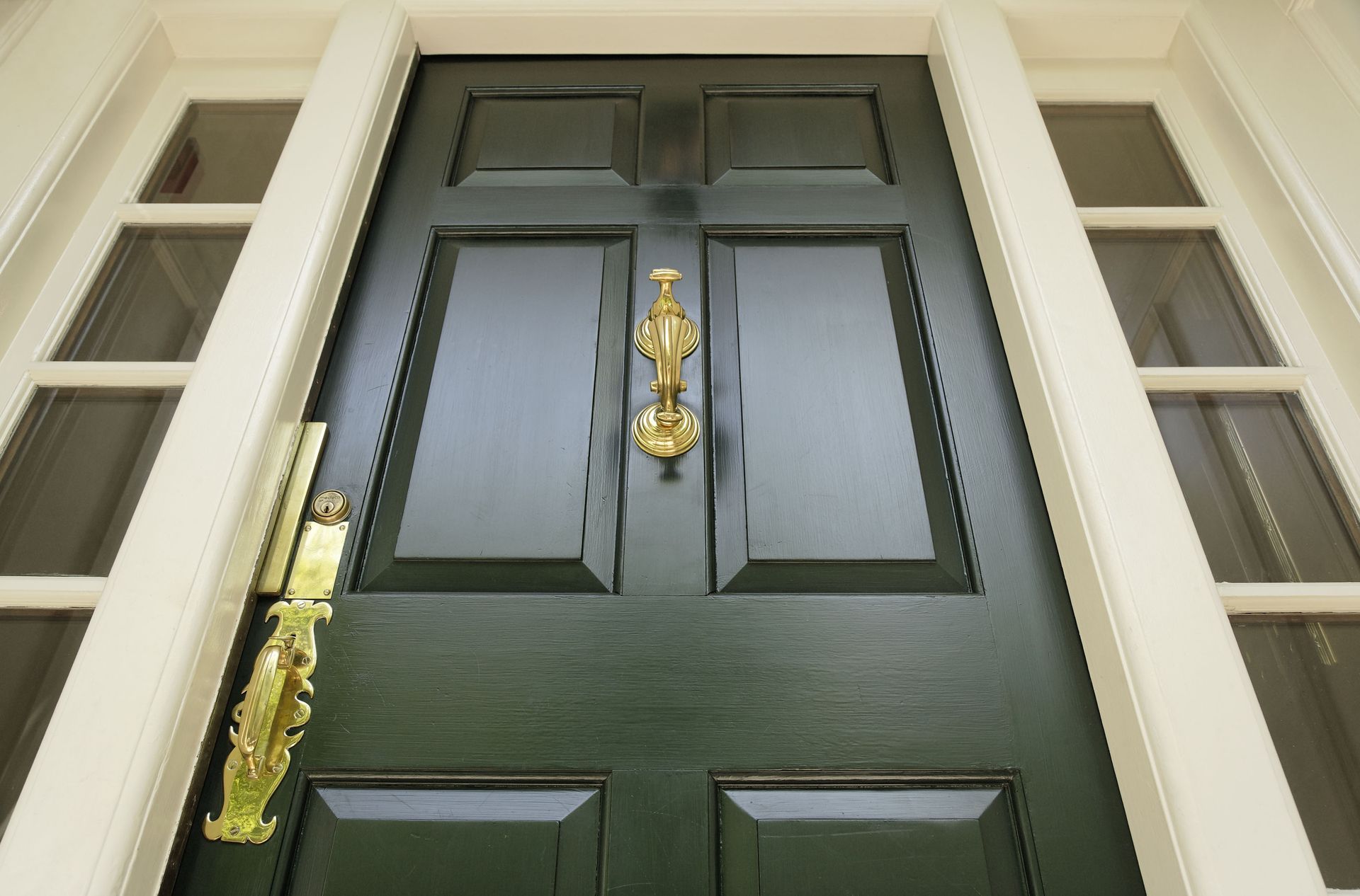 Dark green front door with gold door knocker and hardware.