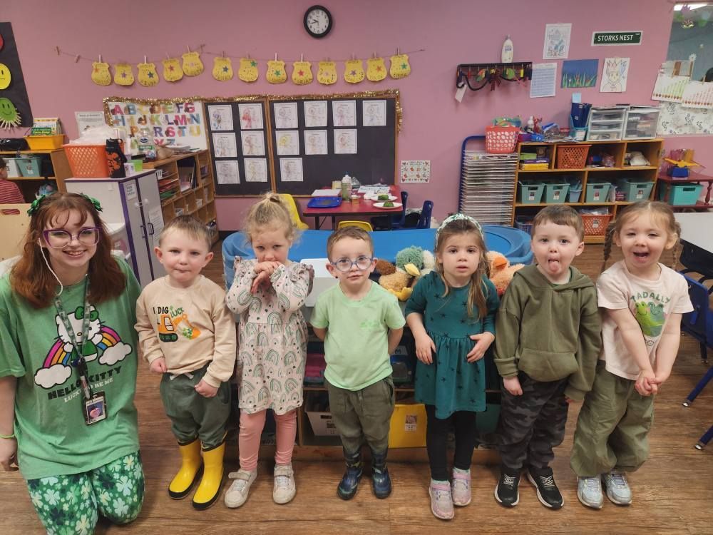 Teacher and children in green clothing in a classroom for St. Patrick's Day.