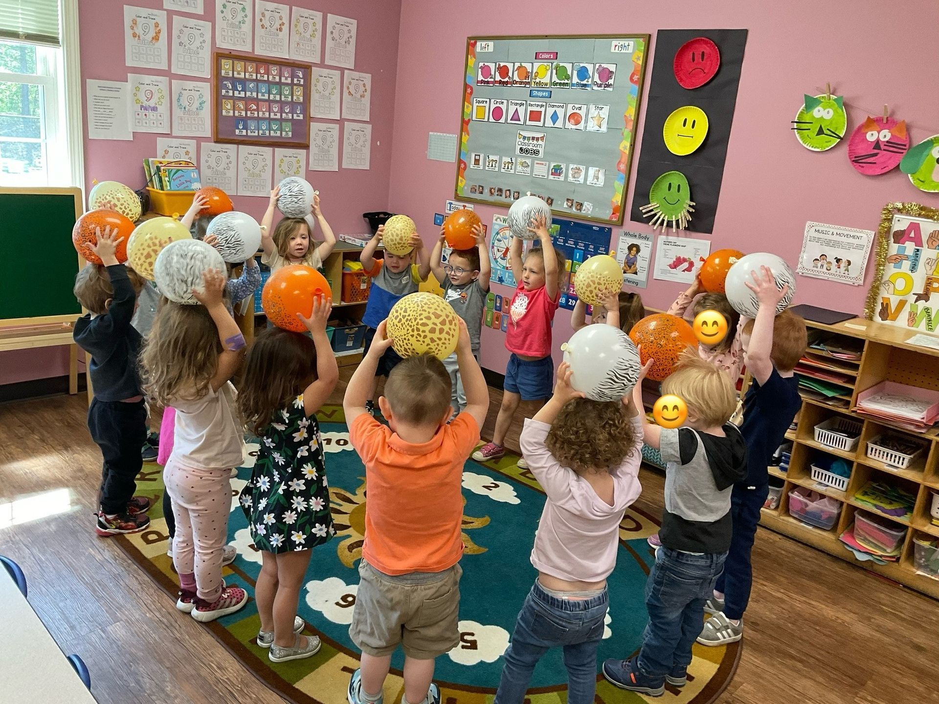 Children in a circle holding up colorful balls in a classroom.
