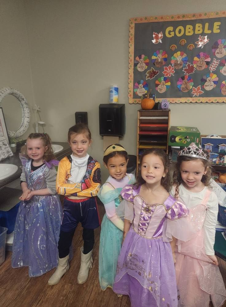 Five children in costumes pose in a classroom, with a 
