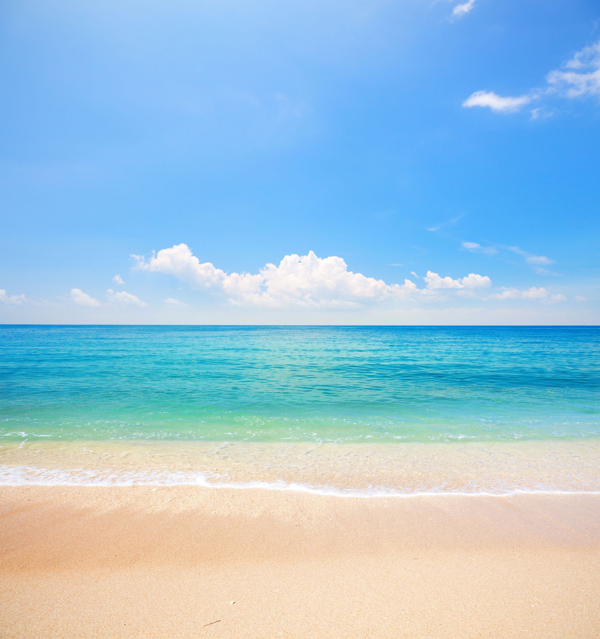 Sunny beach with turquoise ocean, gentle waves, and a clear blue sky