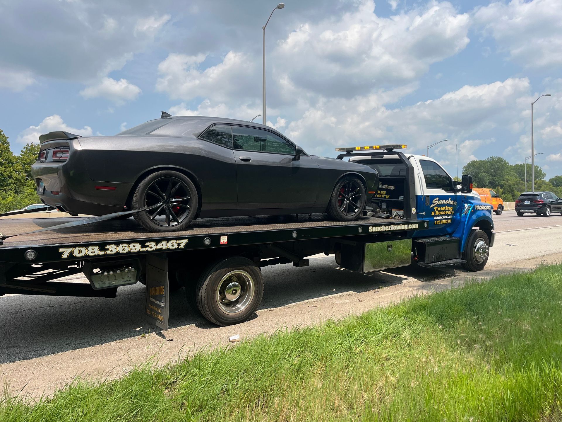 A black dodge challenger is being towed by a tow truck.