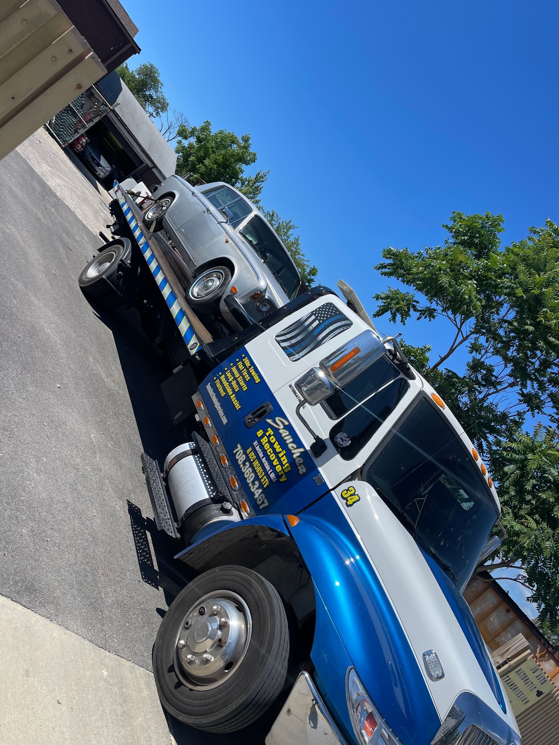 A blue and white tow truck is parked on the side of the road