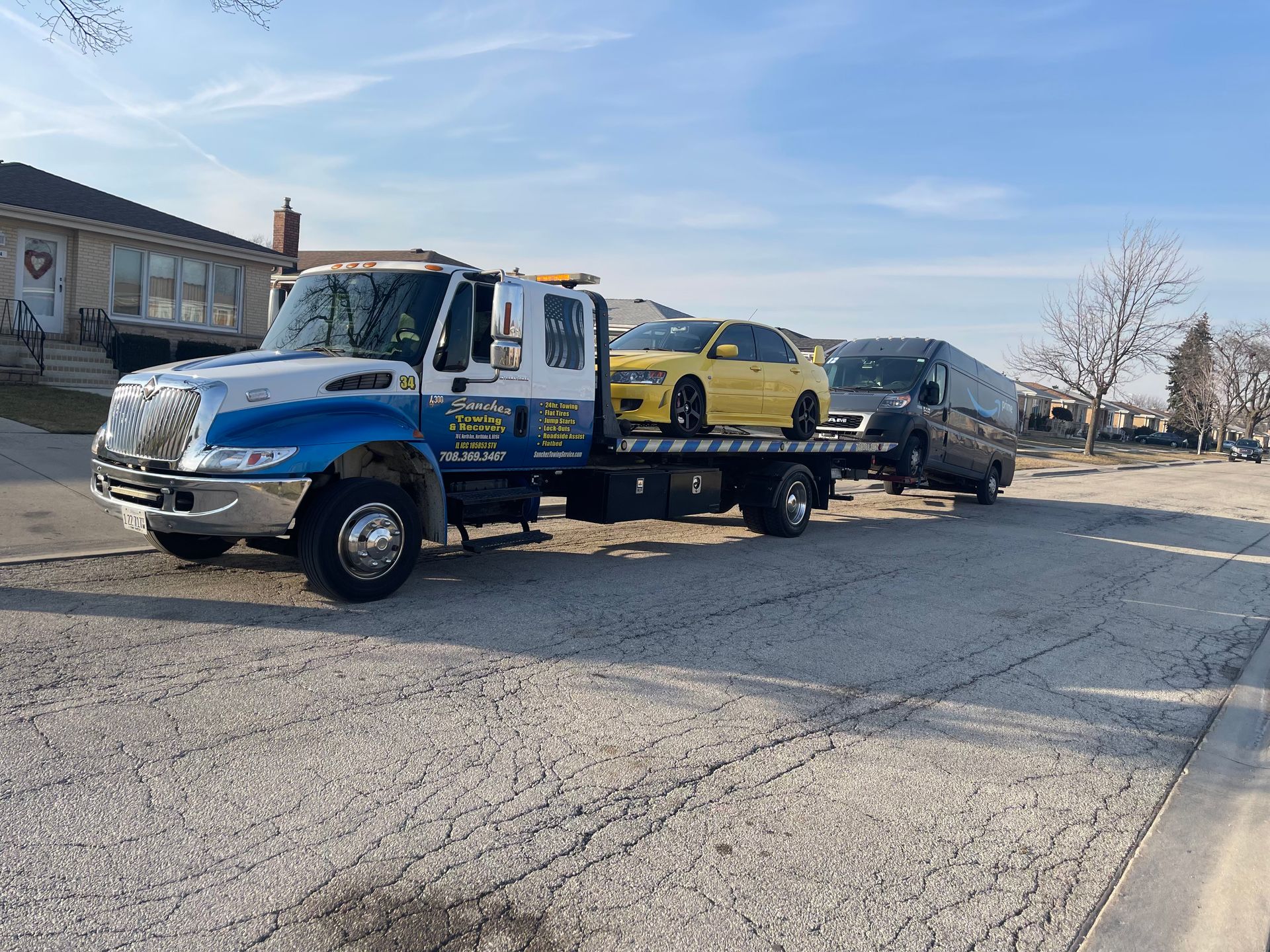 A tow truck is towing a yellow car and a black van.