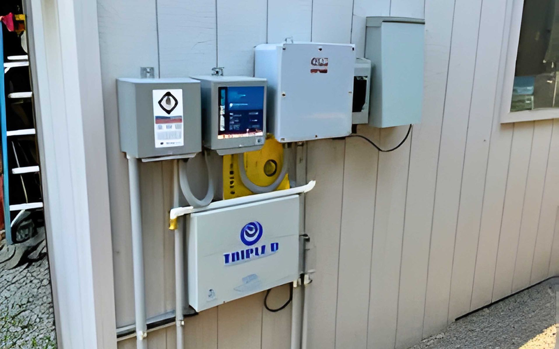 Electrical boxes and panels mounted on a light-colored exterior wall.