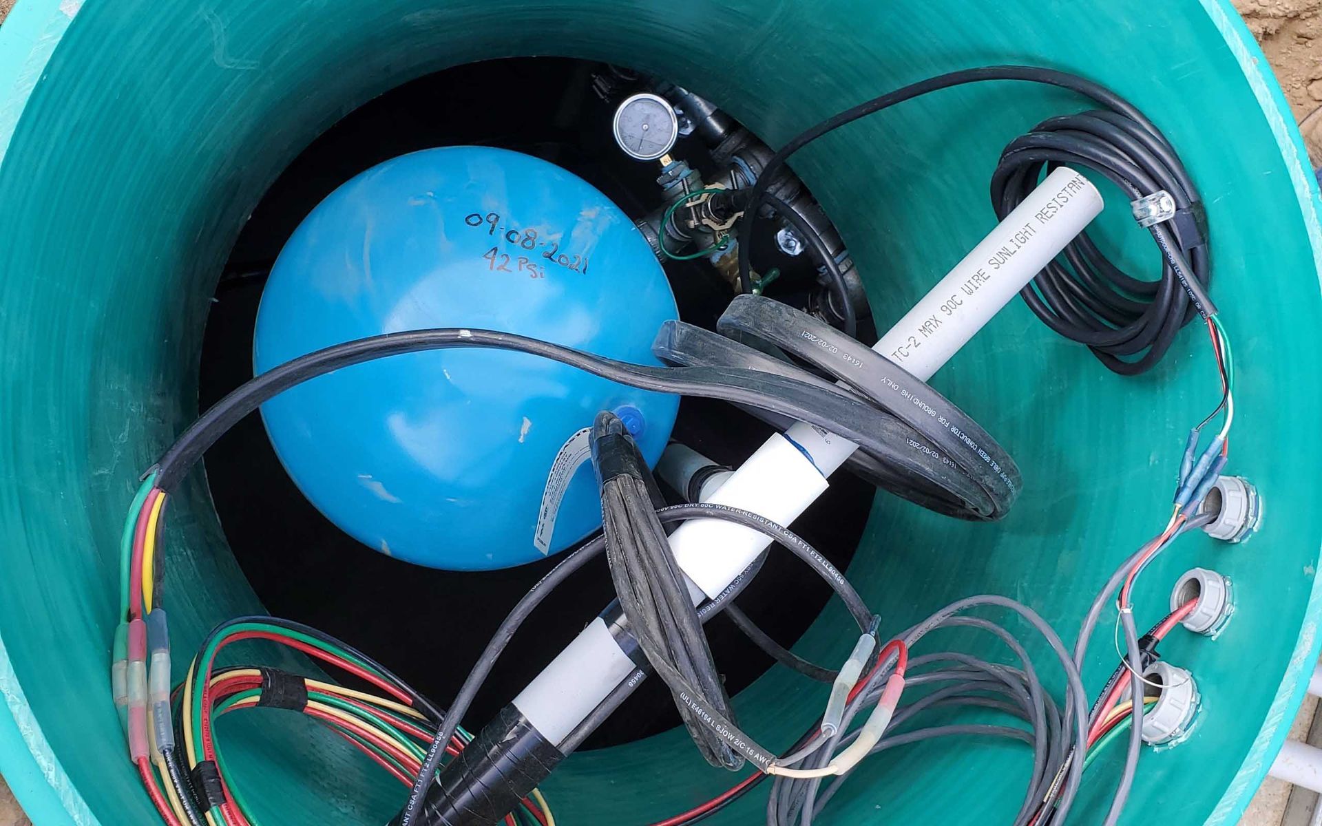 Blue ball and various wires inside a green cylindrical container.