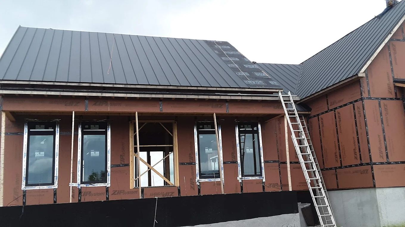 House exterior under construction, with dark roof, windows, and ladder. Brown siding.