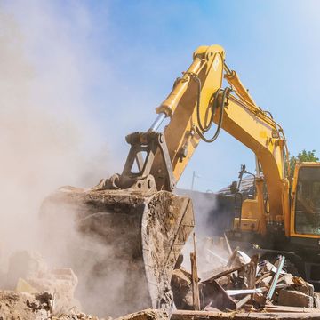 A yellow excavator is working on a construction site.