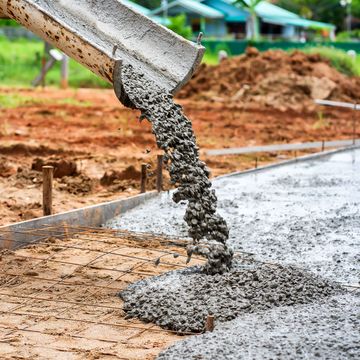 Concrete is being poured into a concrete slab at a construction site.