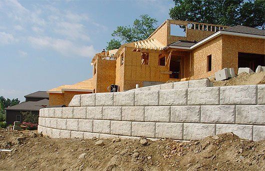 A house is being built on a hill with a retaining wall in front of it
