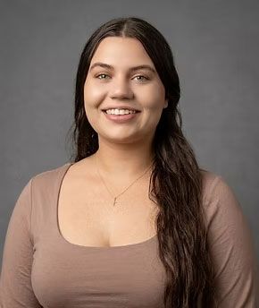 Smiling woman in a taupe top against a gray studio background