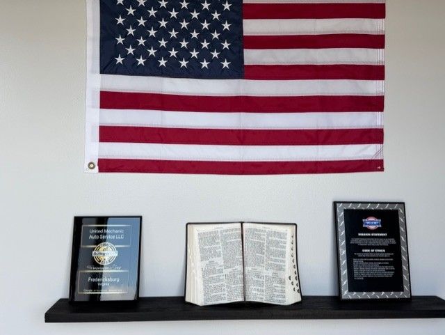American flag above a shelf with an open Bible and two award plaques