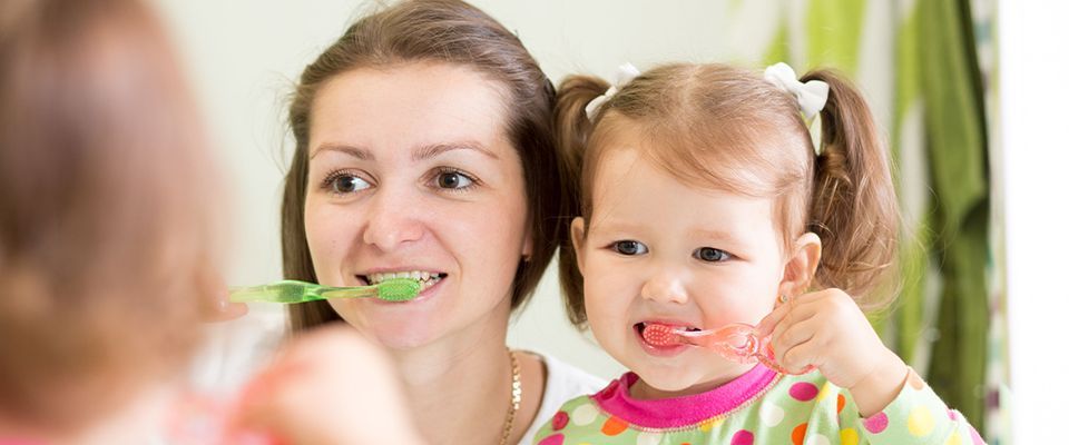 mom teaching daughter child teeth brushing in bathroom