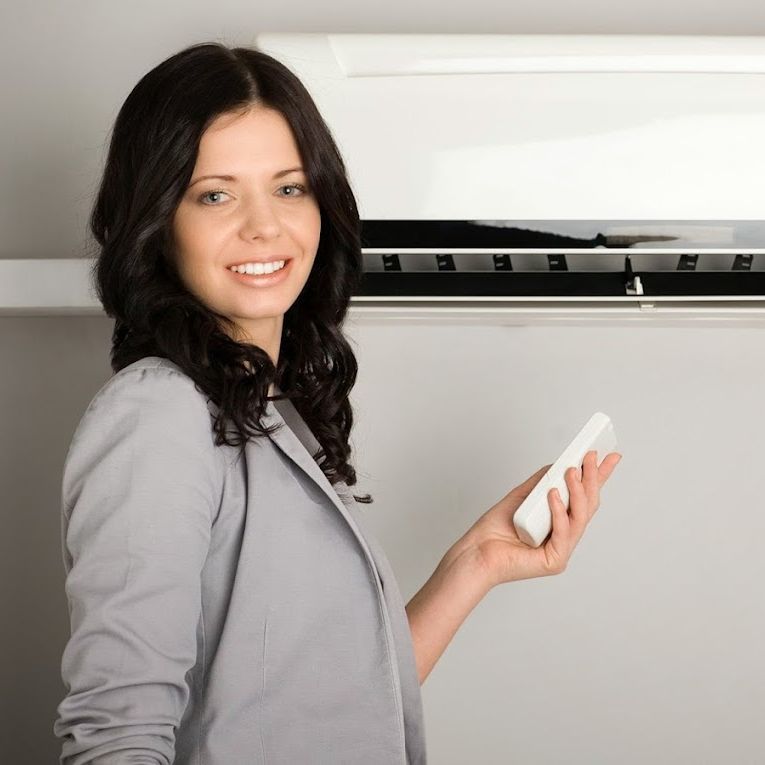 a woman holding a remote control in front of an air conditioner