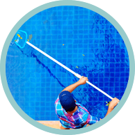 Person cleaning a blue tile pool with a net, seen from above.