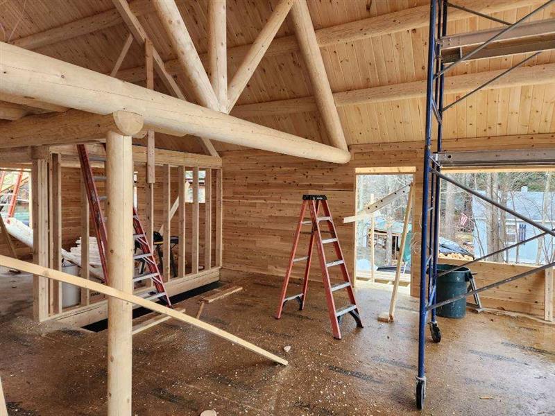 A ladder is sitting in the middle of a wooden room under construction.