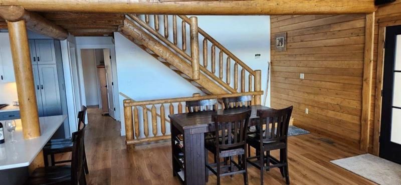 A dining room in a log cabin with a table and chairs and stairs.