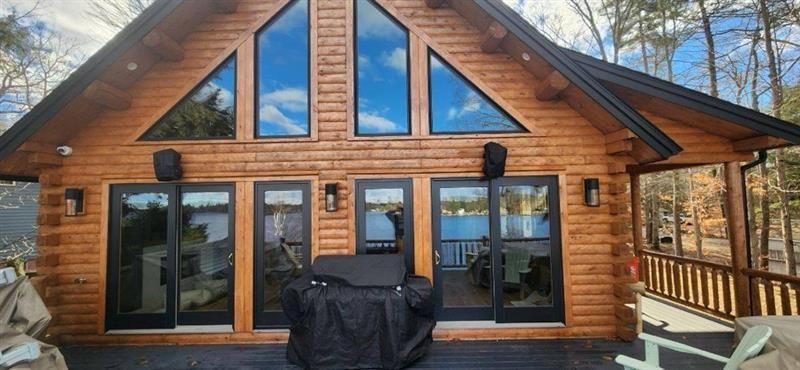 A large log cabin with a grill in front of it.