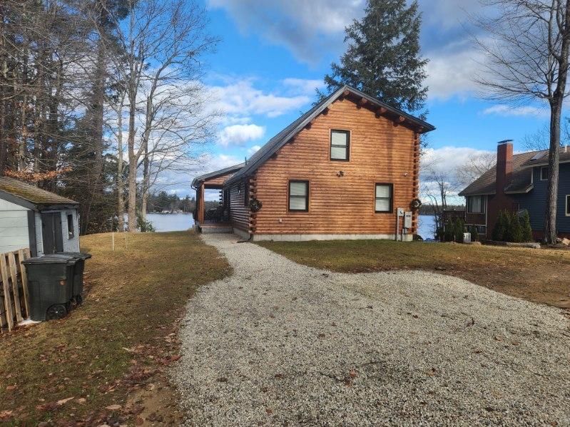 A log cabin with a gravel driveway leading to it