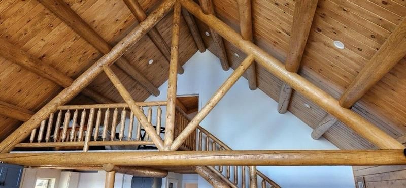 The ceiling of a log cabin with a balcony and stairs.