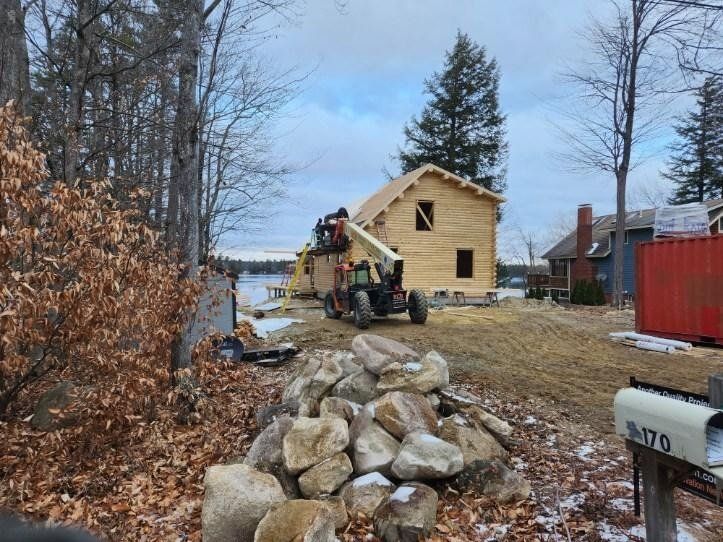 A house is being built in the woods and a pile of rocks is in front of it.
