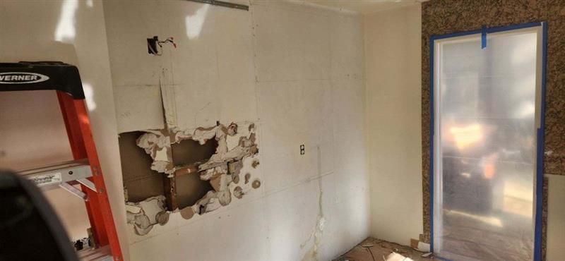 A room with a hole in the wall and a ladder.