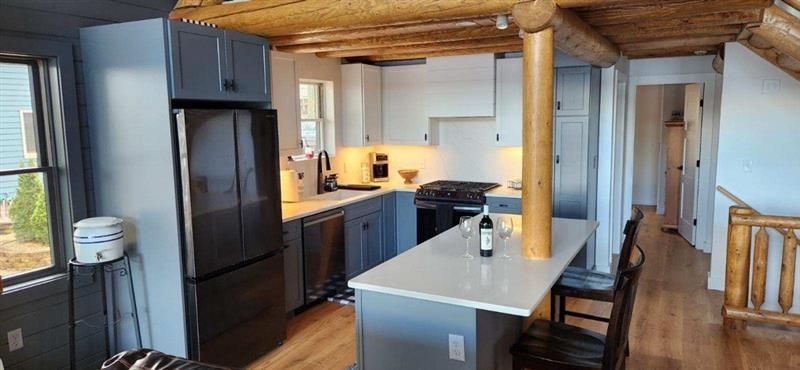A kitchen in a log cabin with a bottle of wine on the counter.