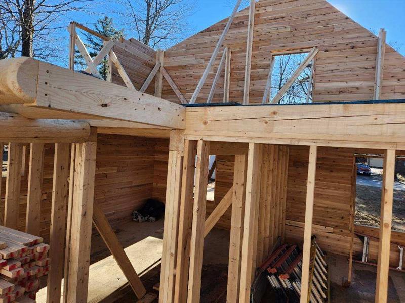 A wooden house is being built in the middle of a forest.