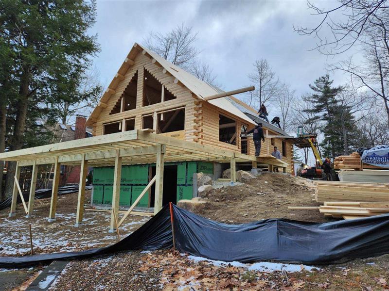 A wooden house is being built on top of a hill.