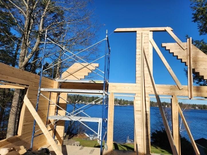 A wooden structure is being built with stairs and a lake in the background