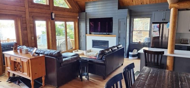 A living room with a couch , table , chairs , television and fireplace.