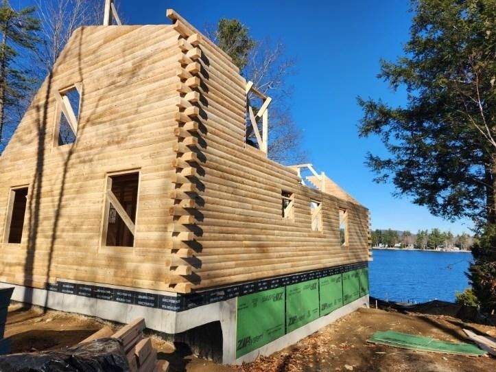 A log cabin is being built next to a lake.