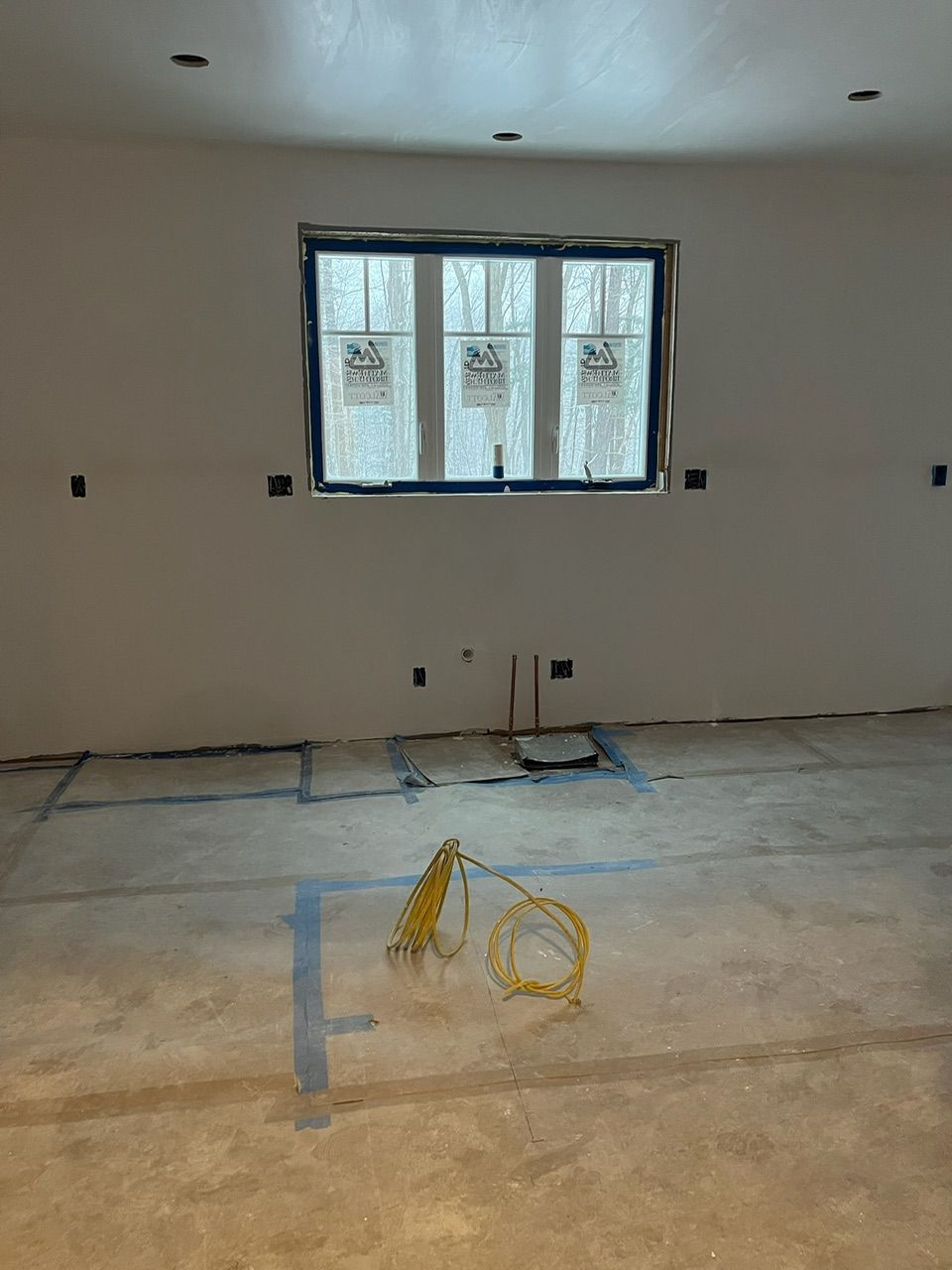 Empty room under renovation with unfinished drywall, window, and exposed wiring on the floor