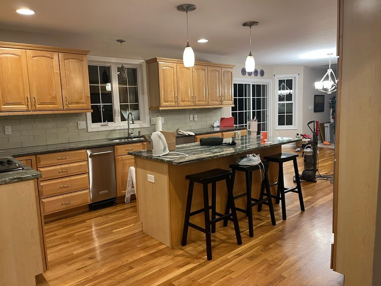 Modern kitchen with wood cabinets, island seating, pendant lights, and hardwood floors